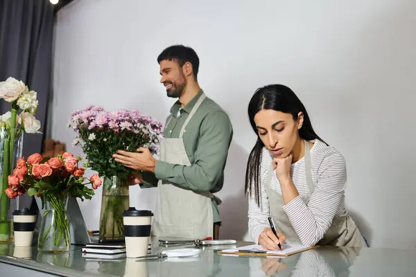 Les propriétaires d'une petite boutique de fleurs collaborent avec passion sur de beaux motifs floraux. — Photo de stock