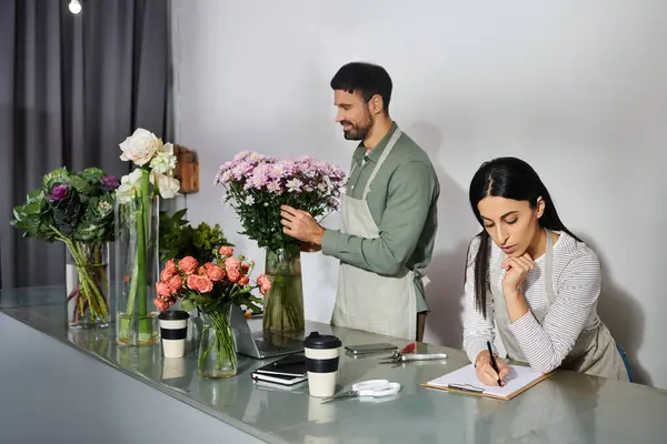 Two florists work side by side in their shop, crafting floral arrangements and managing tasks. — Stock Photo