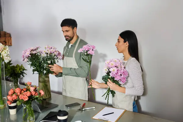 Un equipo de marido y mujer colaboran en su negocio floral, organizando flores coloridas con cuidado. - foto de stock