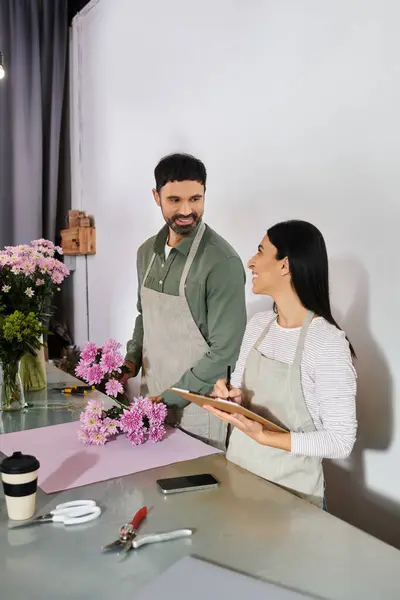 Married couple joyfully preparing beautiful flower arrangements together in their shop. — Stock Photo