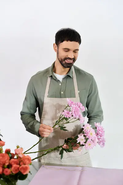 Una floristería hábil artesanía hermosos ramos mientras está rodeado de flores frescas. - foto de stock