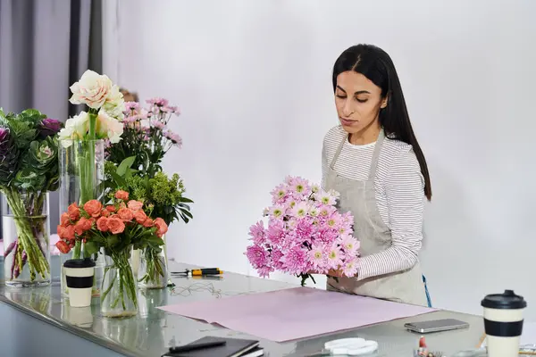 Brunette florist carefully crafts a colorful bouquet from fresh flowers in her shop. — Stock Photo