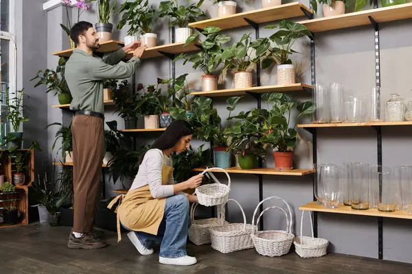 Fleuristes mariés collaborent dans leur magasin de plantes, tendant à la verdure et l'organisation des fournitures. — Photo de stock