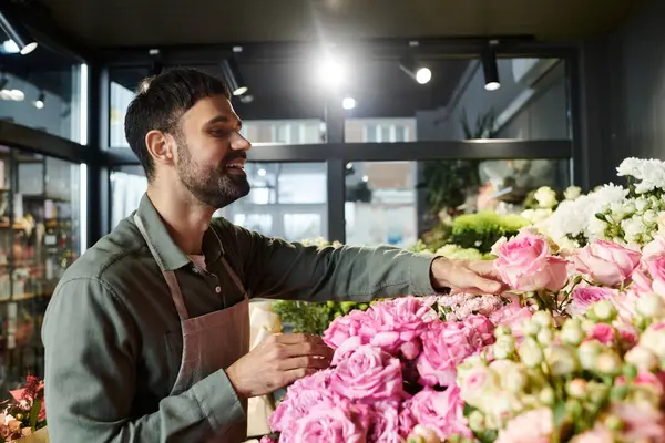 Un florista experto recoge rosas impresionantes, mostrando su pasión y arte en la tienda. - foto de stock