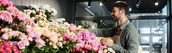 A skilled florist arranges beautiful blooms in his colorful flower shop, showcasing his talent, banner — Stock Photo
