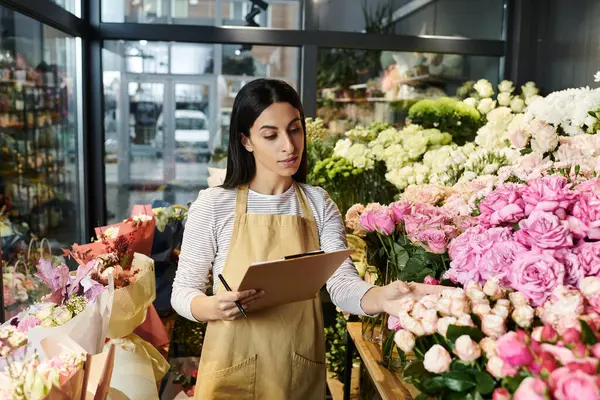 Uma mulher adulta jovem tende a flores bonitas ao gerenciar seu pequeno negócio na loja. — Fotografia de Stock