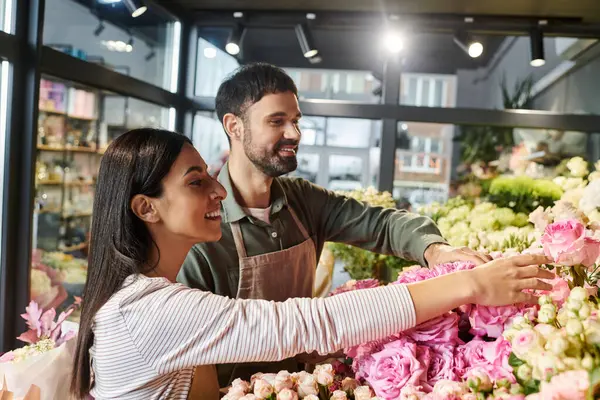 Una pareja dedicada que organiza expertamente flores vibrantes en su querida floristería. - foto de stock