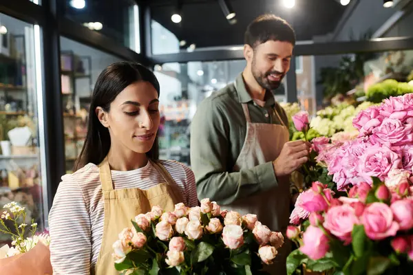 Un marido y una esposa colaboran en su acogedora floristería rodeada de flores vibrantes. - foto de stock
