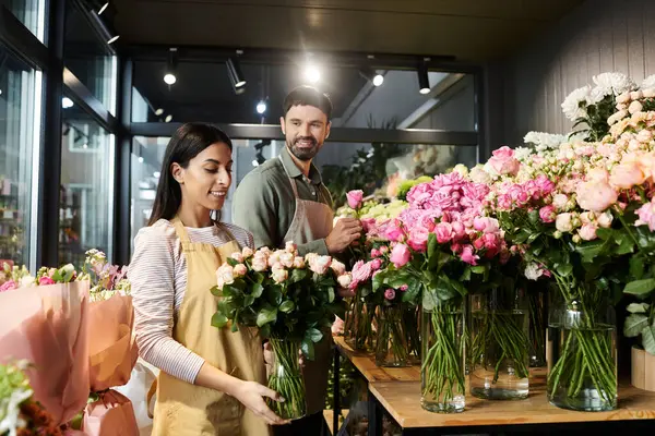 Couple works together arranging roses and other blooms in their vibrant florist shop. — Stock Photo