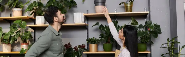 Una florista guía a un cliente masculino a través de una selección de plantas en su encantadora tienda, pancarta - foto de stock