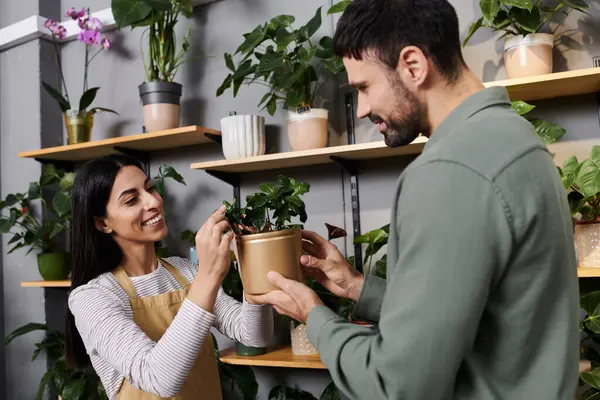 Una floristería amigable ayuda a un hombre a explorar plantas vibrantes en una tienda encantadora. - foto de stock