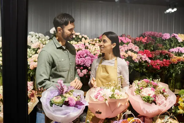 A skilled florist engages with a male client, showcasing vibrant floral designs and arrangements. — Stock Photo