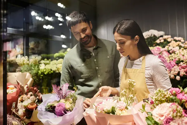 Un fleuriste qualifié guide son client masculin en sélectionnant des fleurs vibrantes, améliorant ses choix. — Photo de stock
