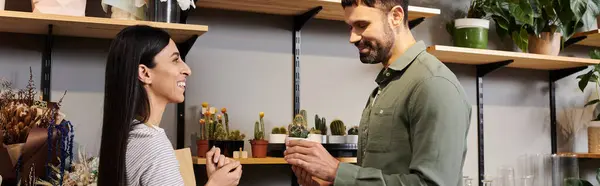 Un florista experto se involucra con un cliente masculino en una vibrante tienda de flores llena de vegetación. - foto de stock