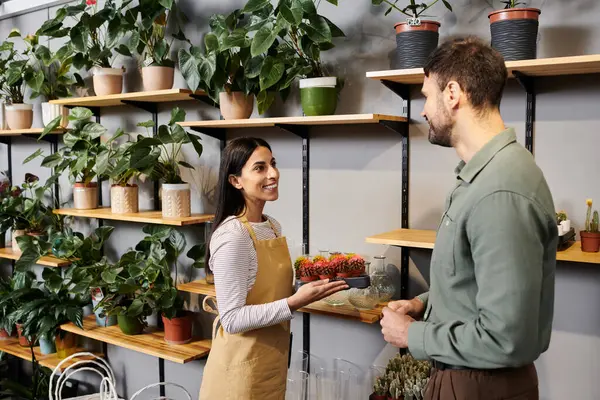 A skilled florist assists a male client, showcasing beautiful plants for selection. — Stock Photo