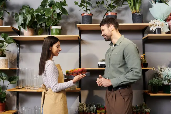 Um florista qualificado ajuda um cliente a escolher plantas em um ambiente acolhedor loja de flores. — Fotografia de Stock