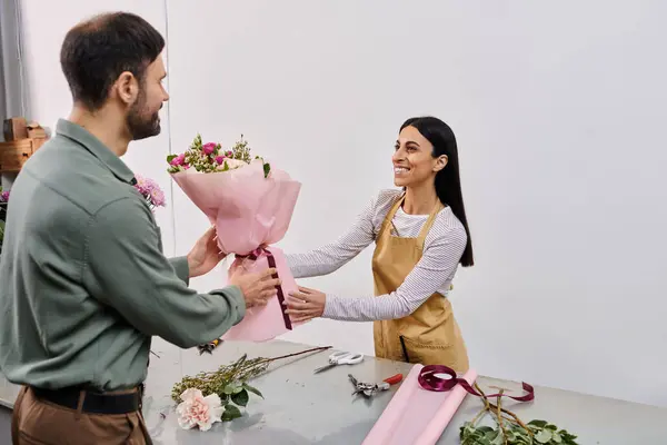 A skilled florist engages with a male client while arranging vibrant flowers in the shop. — Stock Photo