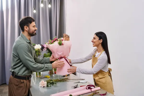 Une fleuriste présente avec enthousiasme un magnifique bouquet à son client masculin dans la boutique. — Photo de stock