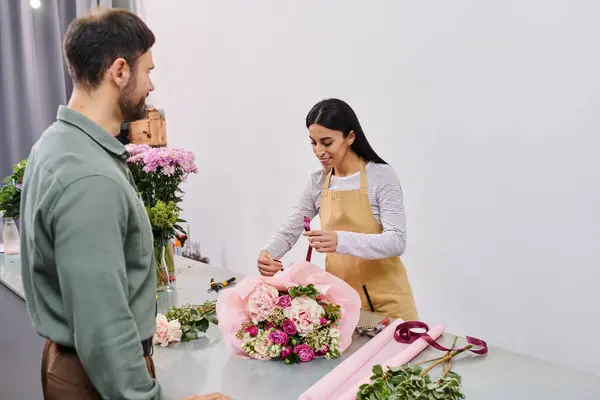 A talented florist designs a stunning bouquet while interacting with a male customer in the shop. — Stock Photo