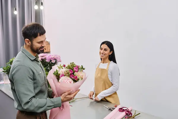Um florista talentoso se envolve com um cliente masculino enquanto mostra um deslumbrante buquê de flores. — Fotografia de Stock