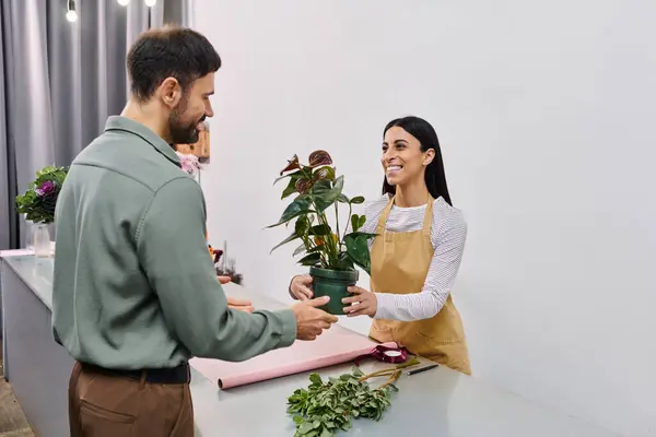 Un fleuriste expérimenté aide joyeusement un client masculin à choisir une belle plante dans son magasin. — Photo de stock