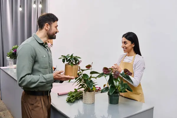 A skilled florist engages with a male client, sharing advice on beautiful plants for his home. — Stock Photo