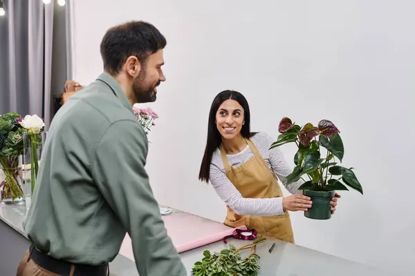 A skilled florist assists a man in selecting beautiful plants during a friendly visit. — Stock Photo