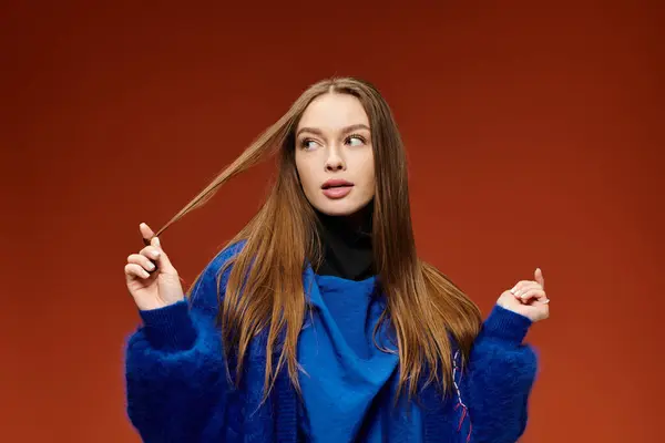 A stylish woman flaunts her vibrant fashion while playfully touching her hair in a bright space. — Stock Photo