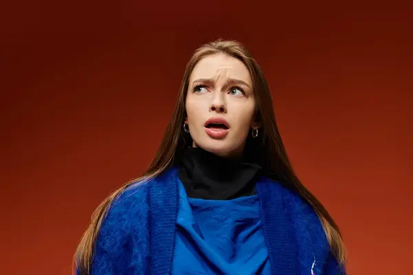 A vibrant stylish woman with long hair looks upwards with a surprised expression on her face. — Stock Photo