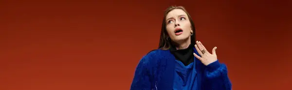 Une femme élégante pose en toute confiance dans sa tenue sur un fond orange vif. — Photo de stock