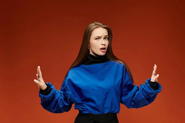 Una mujer confiada en un suéter azul muestra su estilo con un telón de fondo audaz. — Stock Photo