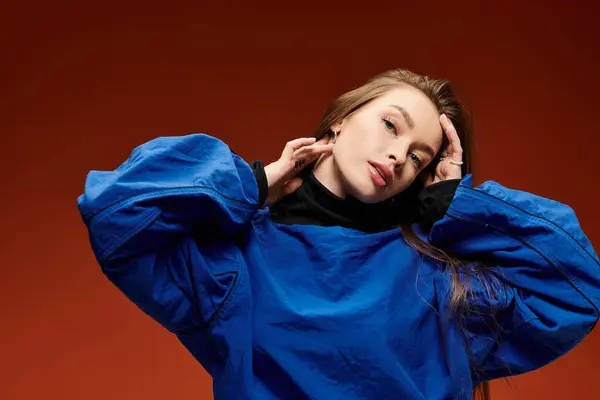 Woman with long hair stylishly poses while showcasing a vibrant blue outfit in a striking setting. — Stock Photo