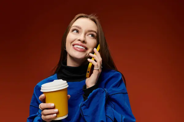 Beautiful woman with long hair enjoys a coffee while chatting on the phone in a cozy environment. — Stock Photo