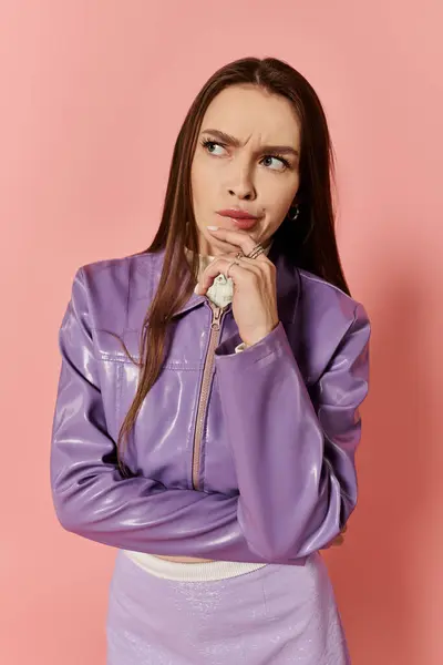 A vibrant stylish woman poses thoughtfully against a bright pink backdrop wearing purple clothing. — Stock Photo