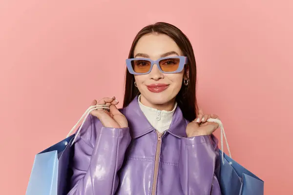 Mujer con estilo posa con bolsas de compras, haciendo alarde de su moda en un ambiente lúdico. - foto de stock