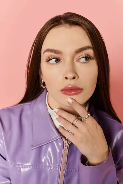 Beautiful woman with long hair in a stylish outfit poses thoughtfully against a pink backdrop. — Stock Photo