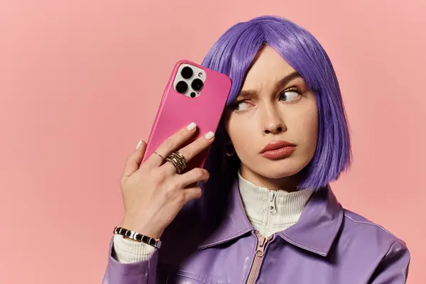 A stylish woman with a purple bob poses with a smartphone against a pink background. — Stock Photo