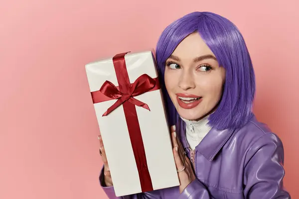 Mujer brillante y alegre con el pelo púrpura sostiene un regalo maravillosamente envuelto con un gran lazo rojo. — Stock Photo