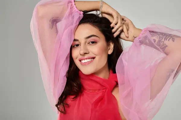 A beautiful young woman poses confidently in a light filled space, wearing a vibrant pink outfit. — Stock Photo