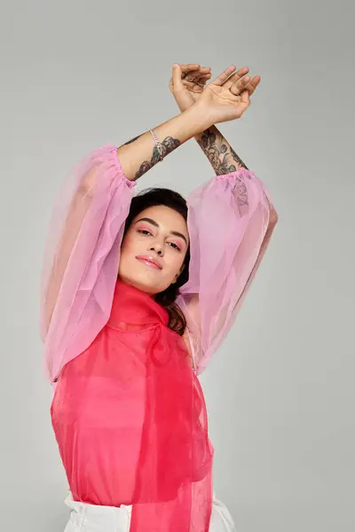 Beautiful woman stretches her arms elegantly, showcasing her stylish attire and tattoos. — Stock Photo