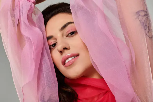 A young beautiful woman showcases her elegance in flowing pink fabric, radiating confidence. — Stock Photo
