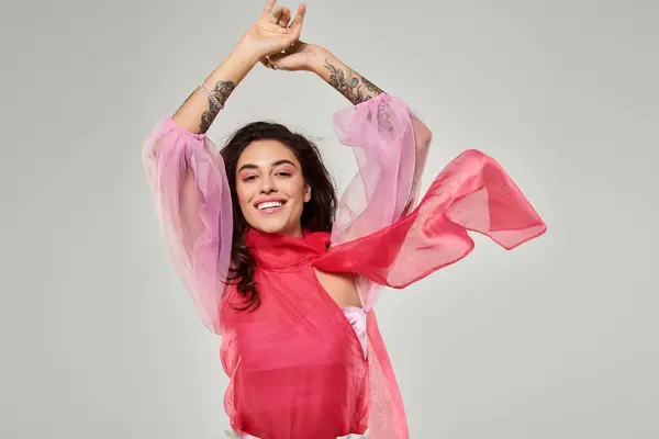 A young beautiful woman joyfully poses with raised arms in colorful attire, radiating happiness. — Stock Photo