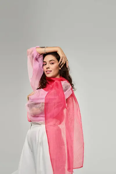 A young beautiful woman displays grace while posing with a colorful scarf in a minimalistic setting. — Stock Photo