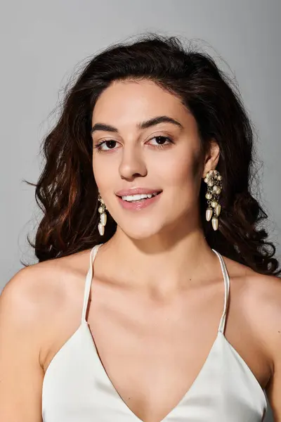 A young beautiful woman smiles confidently, showcasing her stylish earrings and natural curls. — Stock Photo