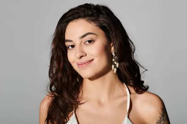 A young beautiful woman displays a charming smile while wearing stylish earrings and casual attire. — Stock Photo