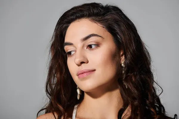 Jeune femme pose gracieusement, soulignant ses cheveux bouclés et sa beauté naturelle dans un éclairage doux. — Photo de stock