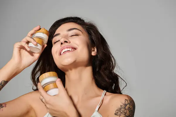 Young woman smiles and applies skincare in a bright, modern, relaxed space. — Stock Photo