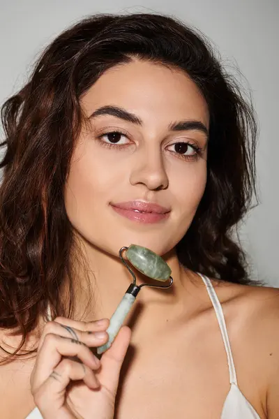 Woman practices self care using a jade roller while enjoying a serene atmosphere at home. — Stock Photo