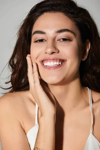 Woman with long hair smiles warmly, exuding confidence and joy in a studio environment. — Stock Photo