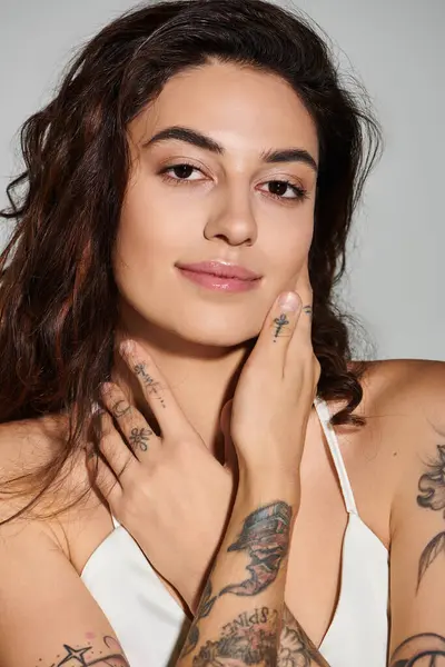 Bella giovane donna mette in mostra i suoi tatuaggi mentre posa in un ambiente luminoso studio. — Foto stock